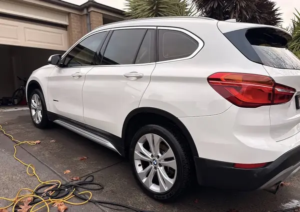 White BMW X1 after an exterior detail, rear three-quarter view, paint still wet