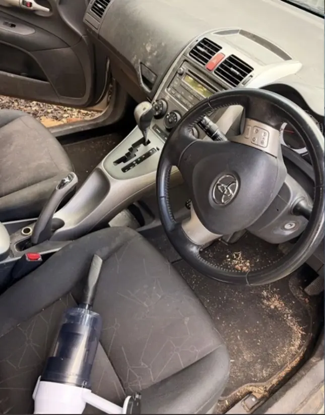 Toyota hatch driver's seat and console before an interior detail, with debris on the seat and floor